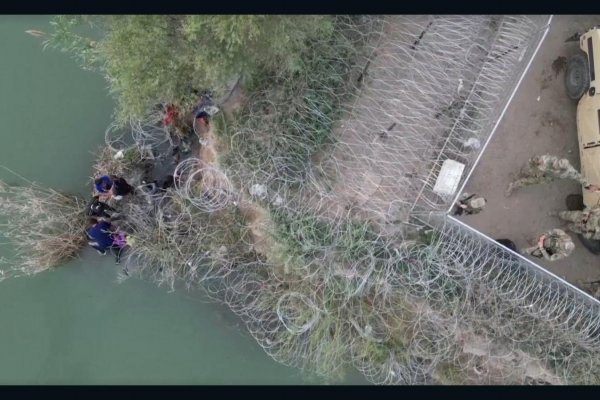 Dron capta a un grupo de migrantes trepando la valla de alambre de púas en Eagle Pass